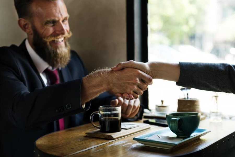 bearded-man-shaking-hands-at-a-table.jpg